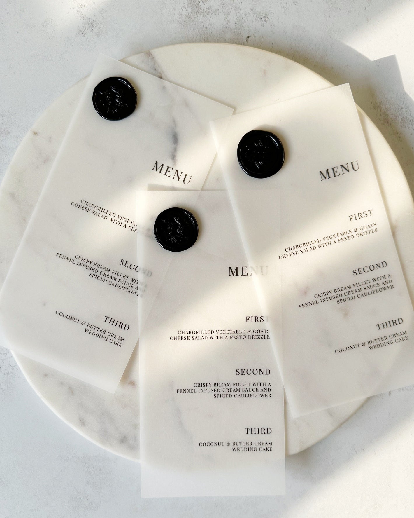 Three menu cards on a marble board with wax seals